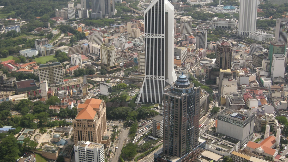 An aerial view over central Kuala Lumpur shows the tall Maybank Tower rising above low rooftops and other office towers
