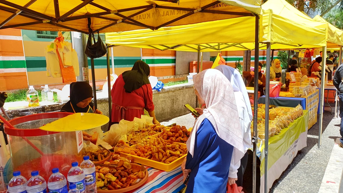 A shopper checks her phone beside a food stall at Kuala Lumpur’s Jalan Benteng market