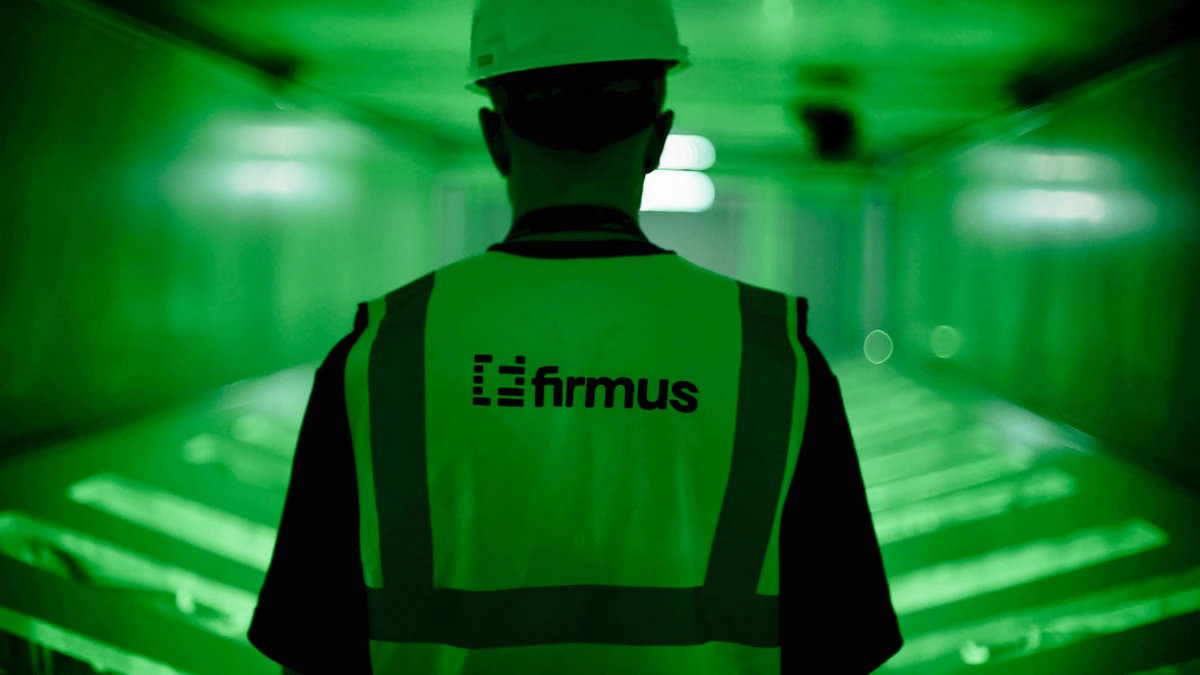 Firmus worker in hard hat and high-visibility vest walking through a green-lit HyperCube immersion cooling aisle