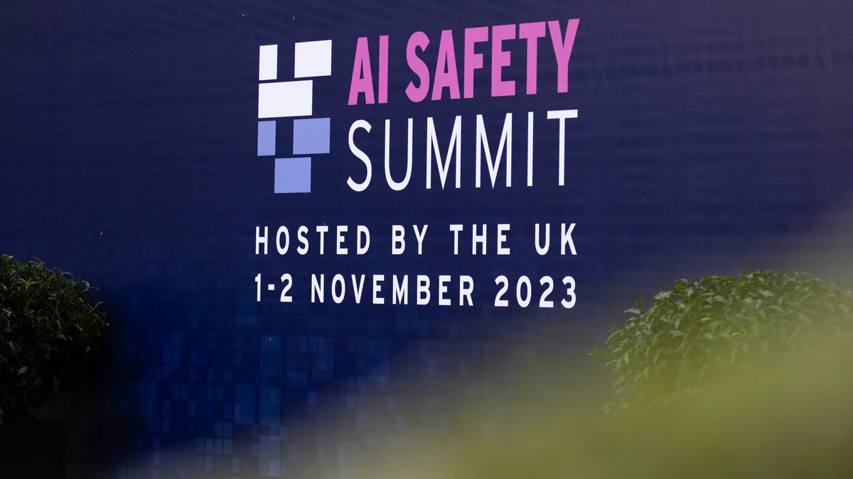 A dark blue event sign reading AI Safety Summit, hosted by the UK, 1 to 2 November 2023, framed by blurred leaves